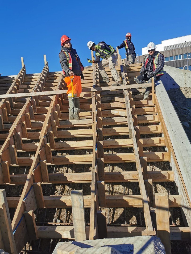 Construction crew standing on wooden stair formwork structure during concrete project in Calgary by Vancal Concrete LTD.