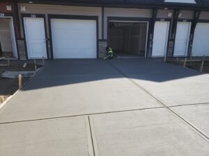 Freshly poured concrete driveway with broom finish in front of Calgary townhomes, completed by Vancal Concrete LTD.