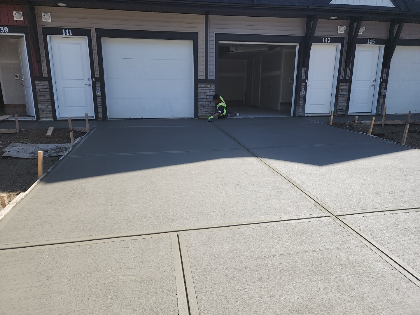 Freshly poured concrete driveway with broom finish in front of Calgary townhomes, completed by Vancal Concrete LTD.